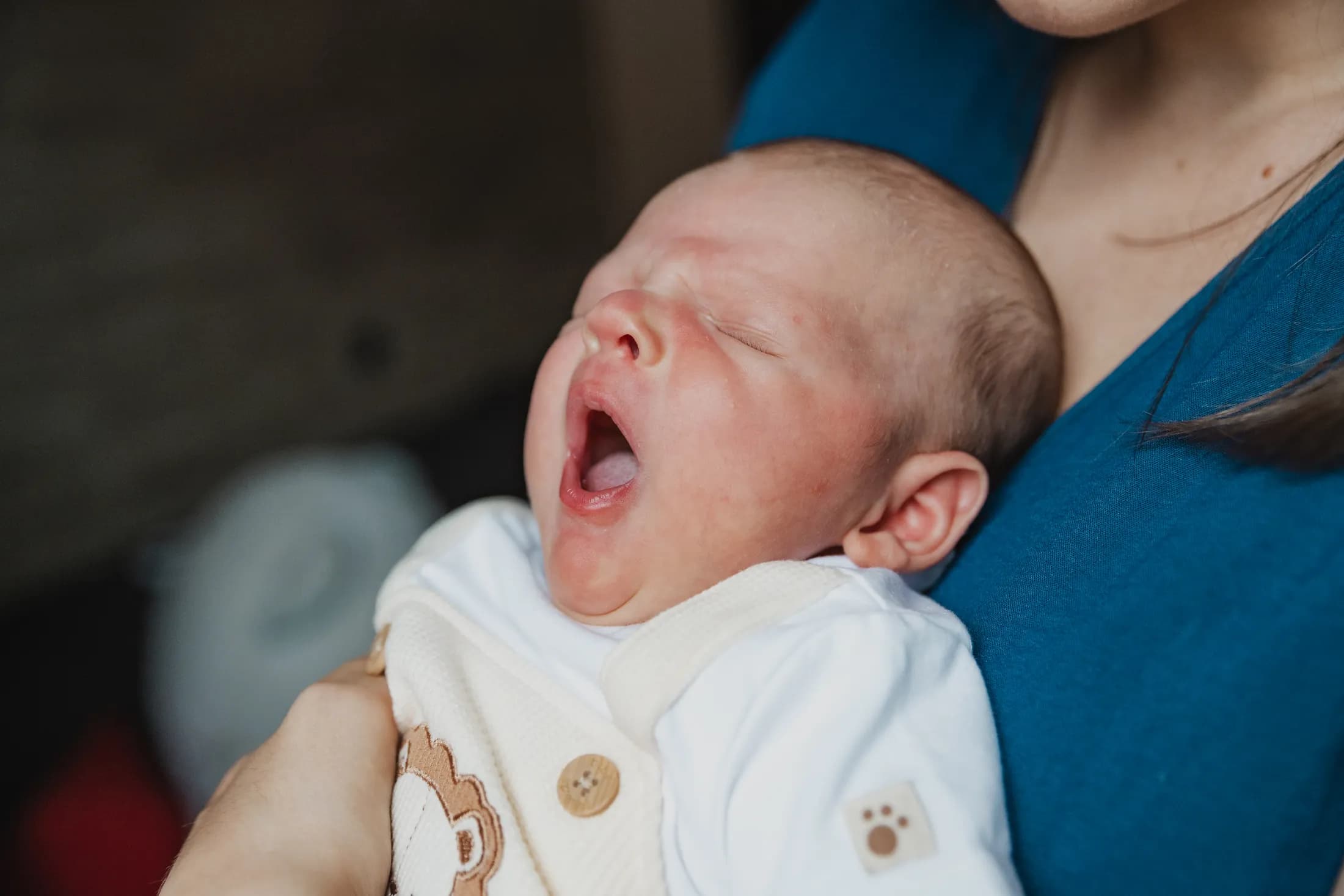 Un neonato sbadiglia appoggiato al petto della mamma